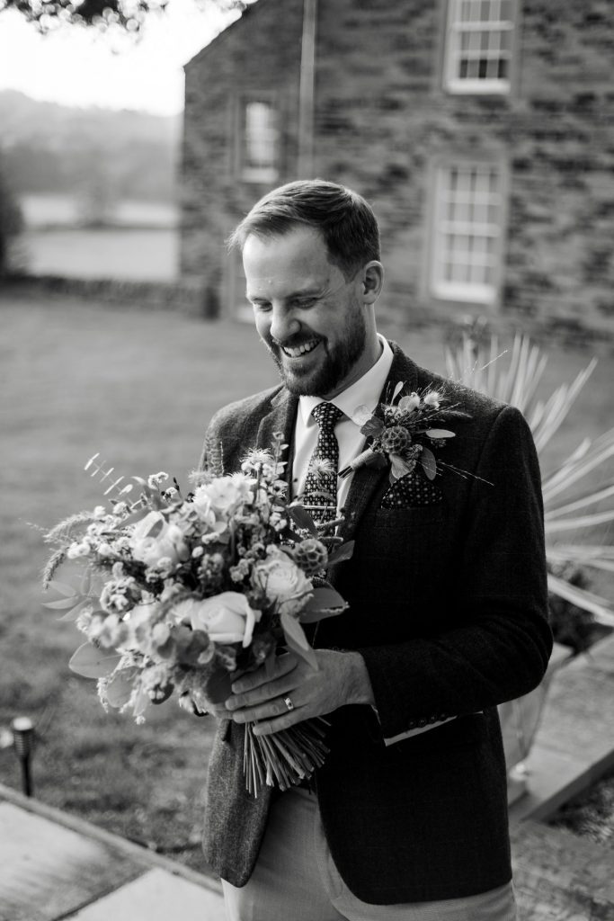 Groom poses with her autumnal wedding flowers at a micro wedding at The Cavendish Hotel