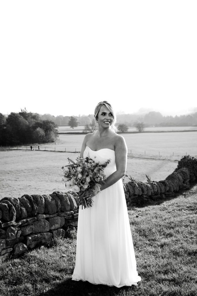 Bride poses with her autumnal wedding flowers at a micro wedding at The Cavendish Hotel