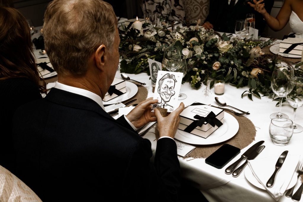 Wedding guest admiring wedding favour caricature at the wedding breakfast of their Micro wedding at The Cavendish Hotel