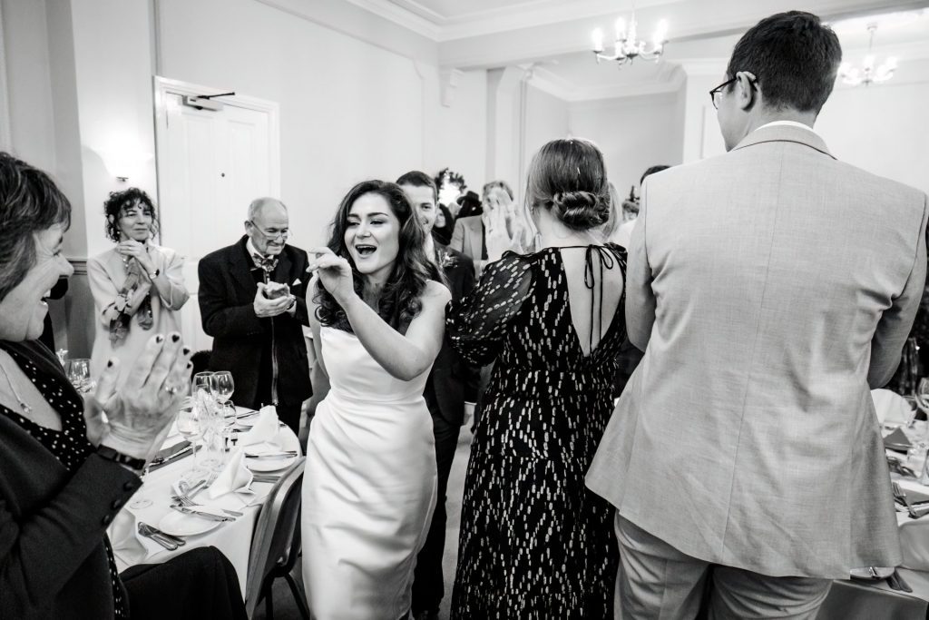 Candid photo announcing the Bride & Groom to the Wedding Breakfast at the Monsall Head Pub. Photo in black & white.