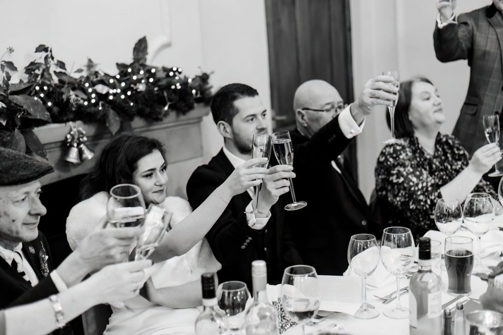 Candid photo of Bride & Groom clinking glasses during the wedding speeches at the Monsall Head Pub. Photo in black & white.
