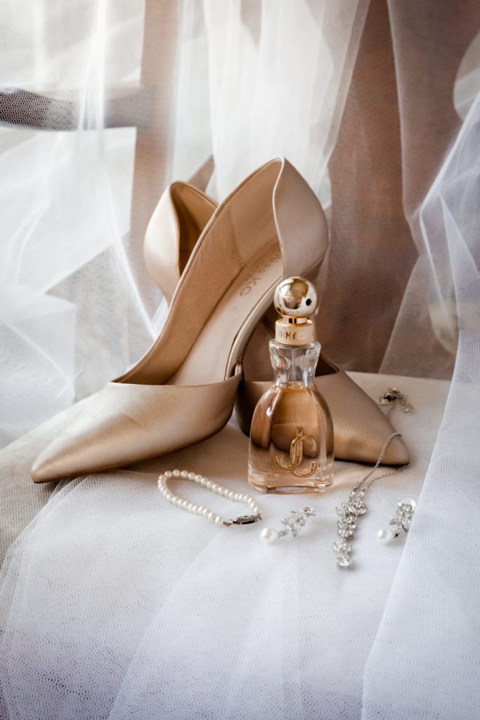 Close-up of the bride's wedding perfume with wedding shoes and wedding jewellery during the bridal prep