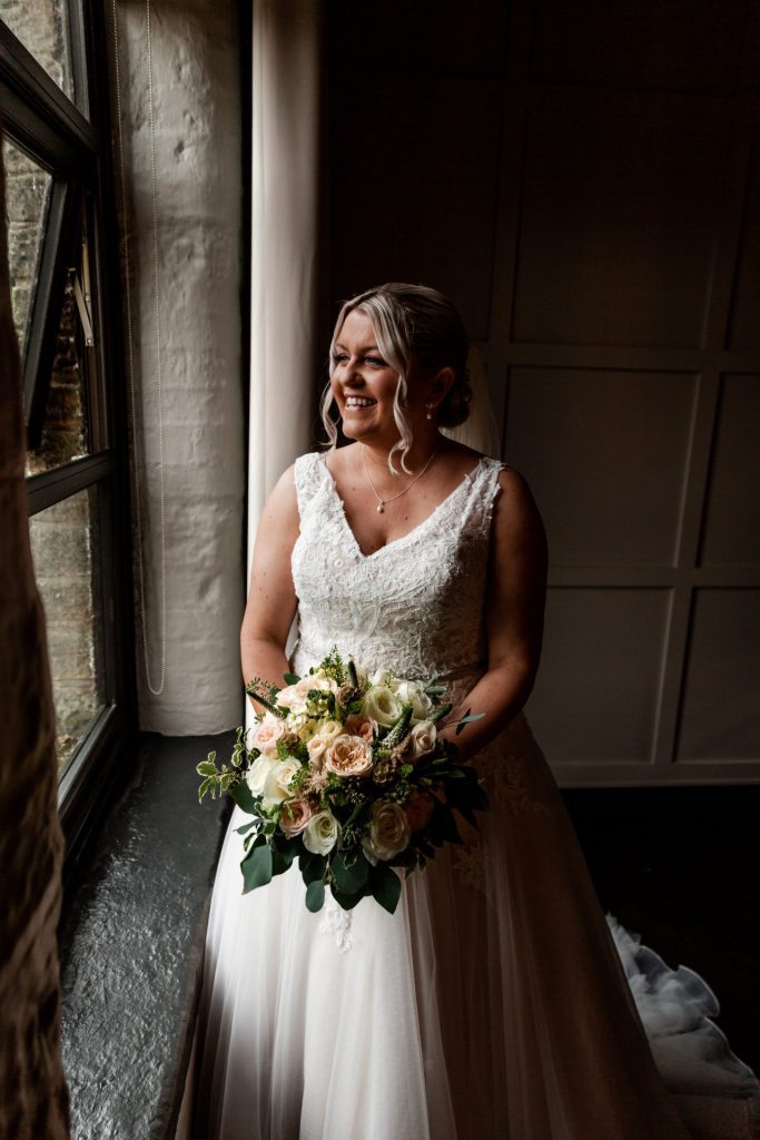 The bride posed in her wedding dress with her bridal bouquet next to the window