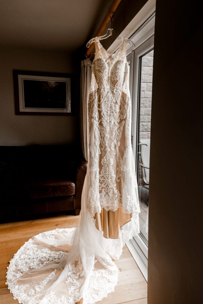 Lace wedding dress hanging in the bedroom during bridal prep
