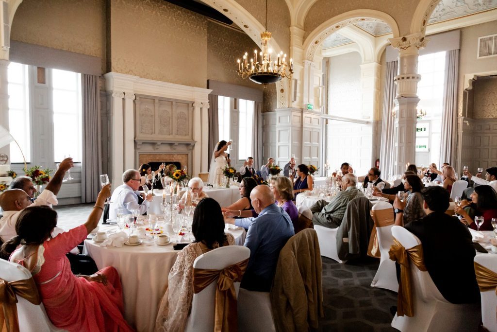 Overview shot of the whole wedding party raising a glass of prosecco during the bridal speech