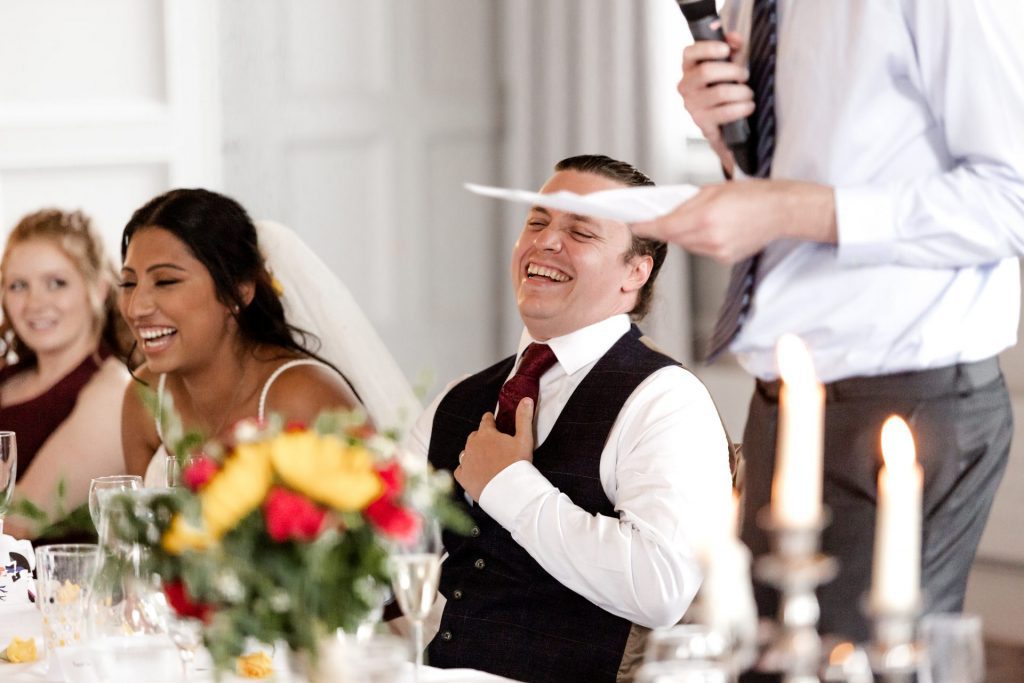 Close in shot of the groom laughing during the best man speech