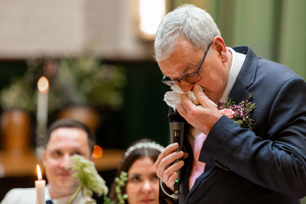 Father of the bride wiping his nose whilst giving a speech