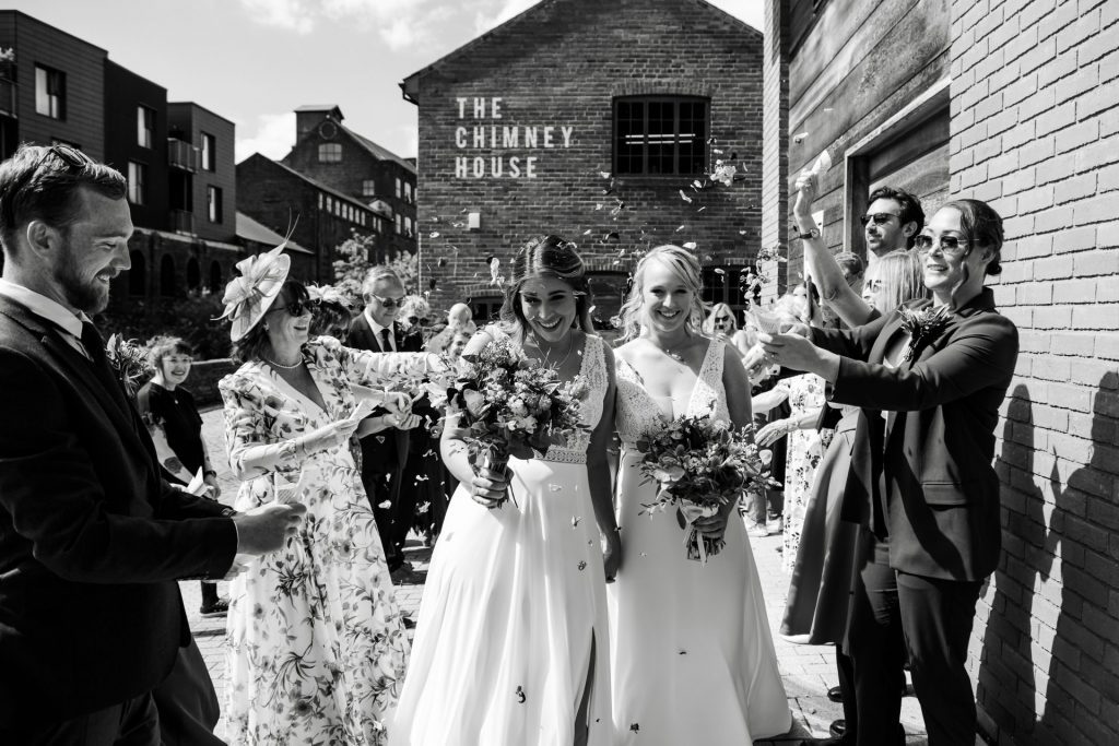 Confetti shot of the bride & bride walking walking through their confetti tunnel at The Chimney House wedding venue, Kelham Island, Sheffield. Isabelle B Photography