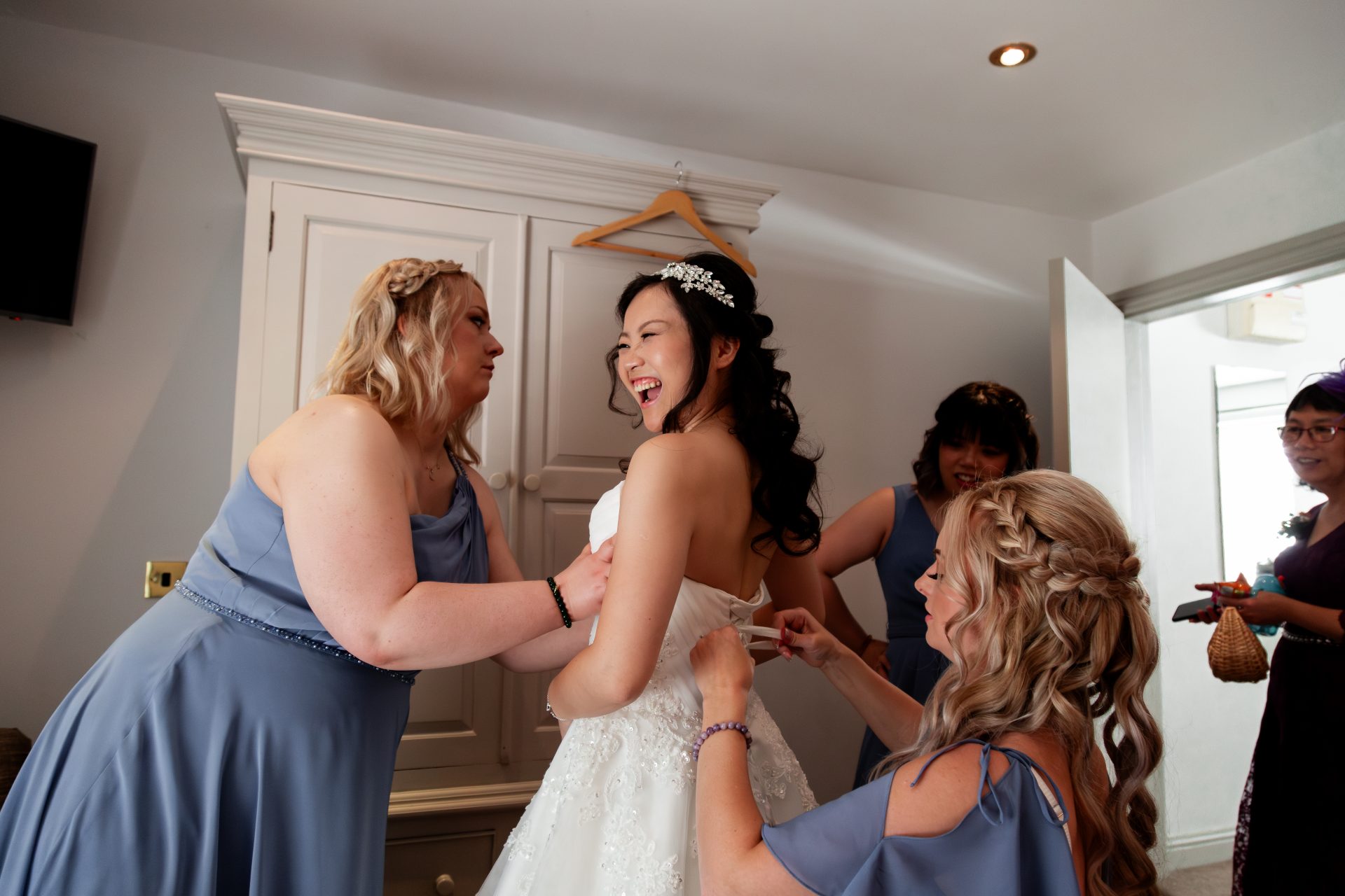 Bride being helped into her dress by her bridesmaids