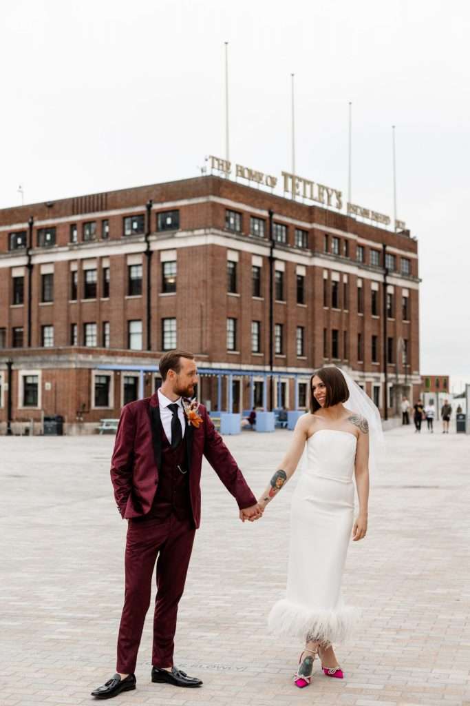 Newly married couple Abi & Adam, standing together hand-in-hand outside their wedding venue, The Tetley, Leeds. Isabelle B Photography 