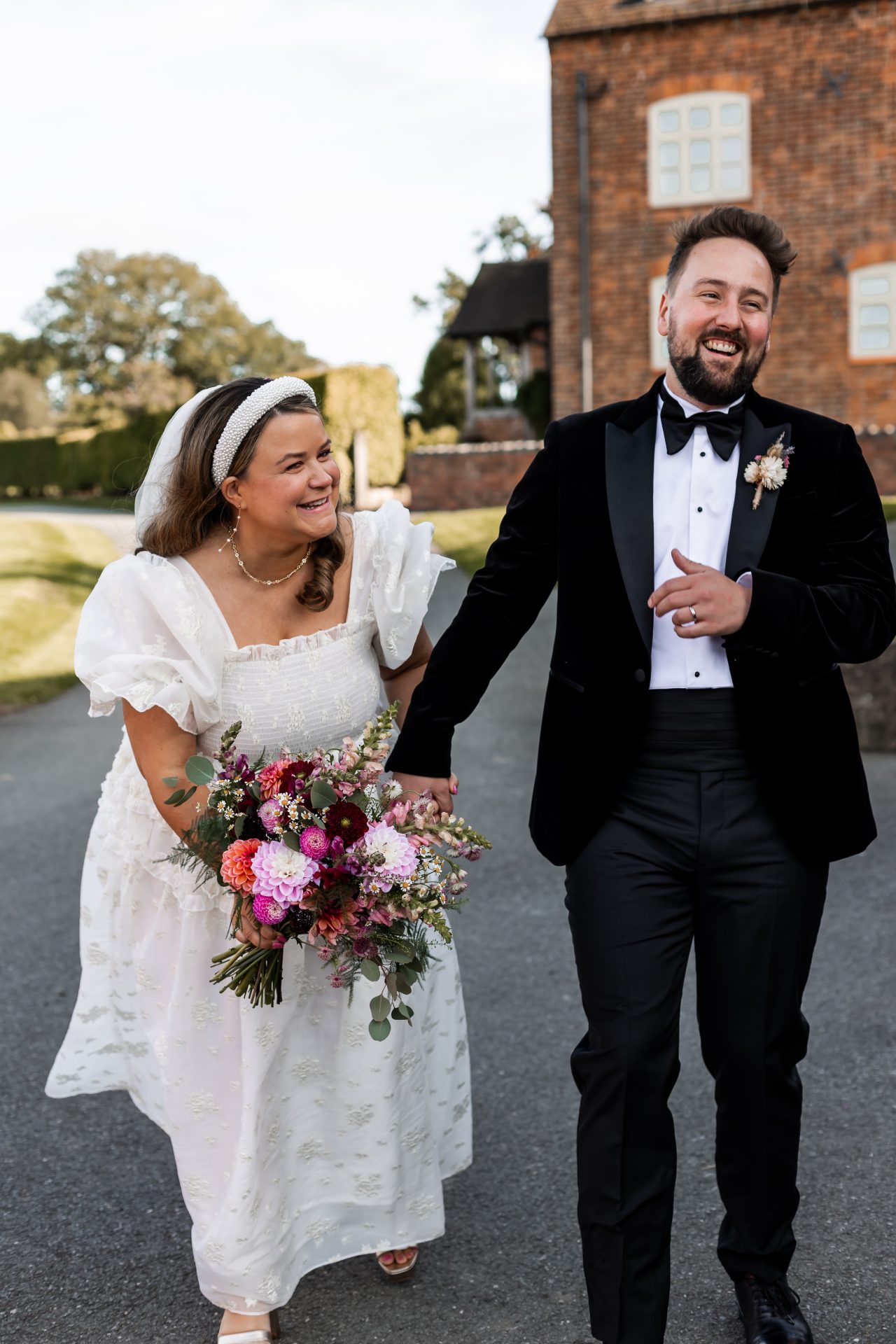 Newly married couple Catherine & Charlie, walking together hand-in-hand outside their wedding venue, Grange Barn, Cheshire. Isabelle B Photography
