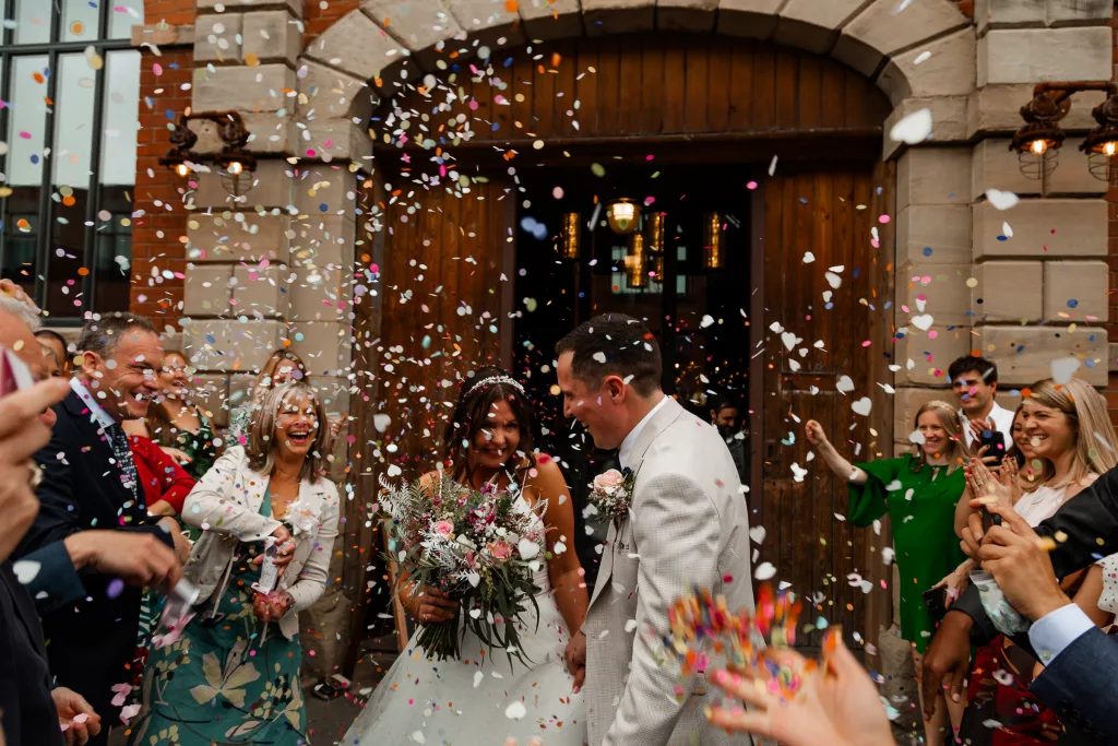 Action shot of the Bride & groom as confetti rains down on their outside their wedding venue, The Mowbray, Sheffield