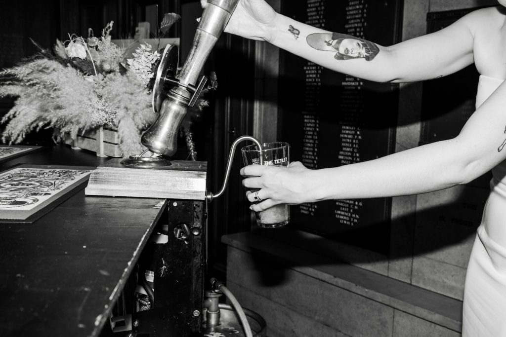A close up shot of the bride pulling a pint at The Tetley, Leeds as an alternative to cutting the cake - black & white
