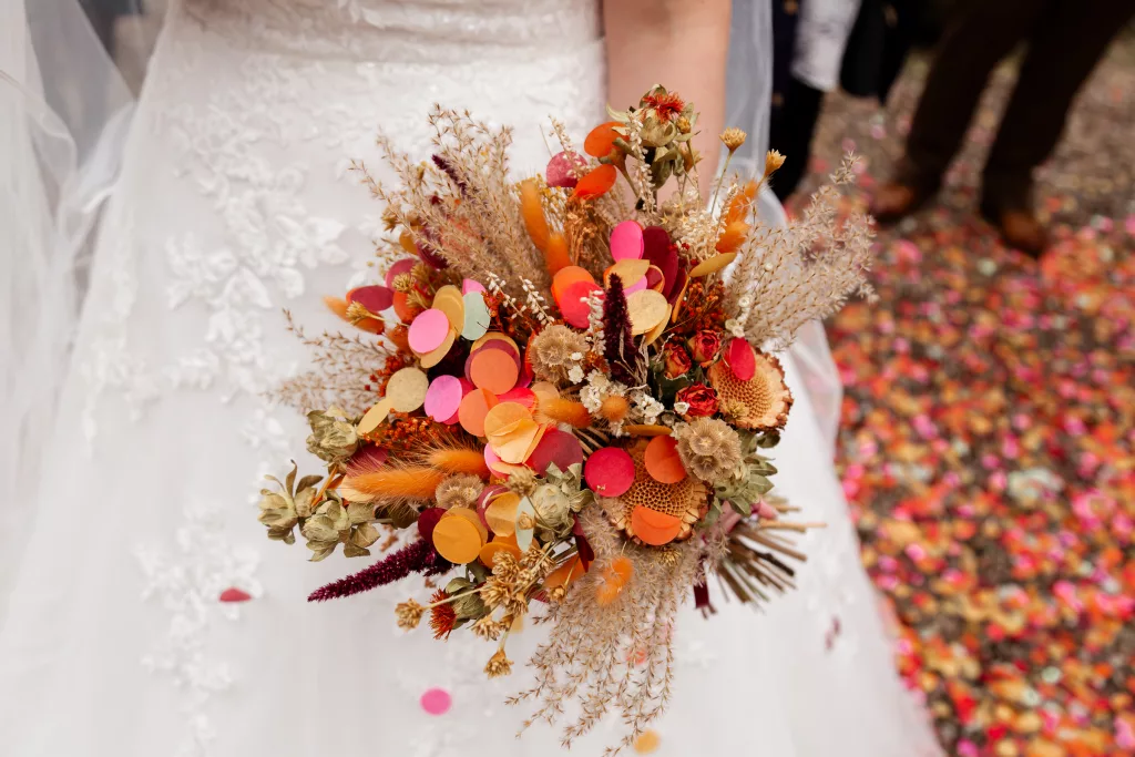 Close up shot of the brides dried flower bouquet which is covered in paper confetti from Flutter Darlings confetti