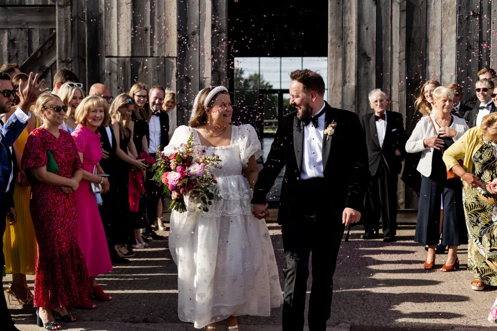 Newly married bride & groom walking through their confetti tunnel