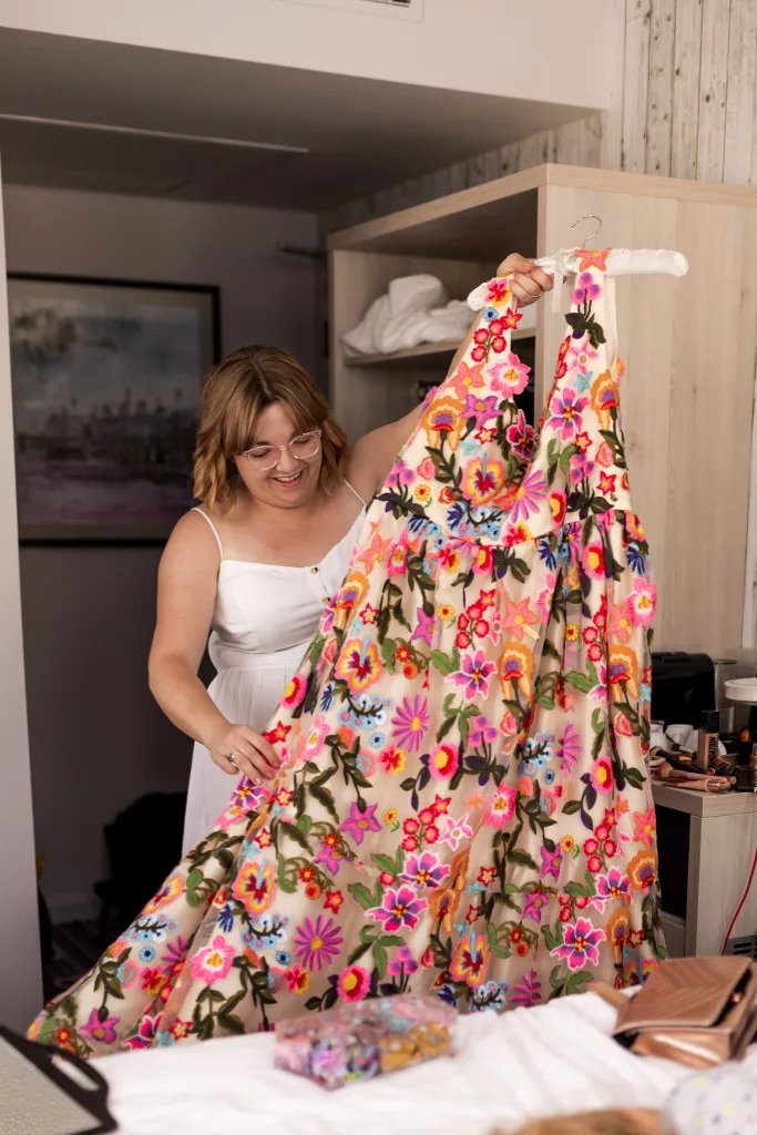 The bride holding up her multicoloured wedding dress during her bridal prep.