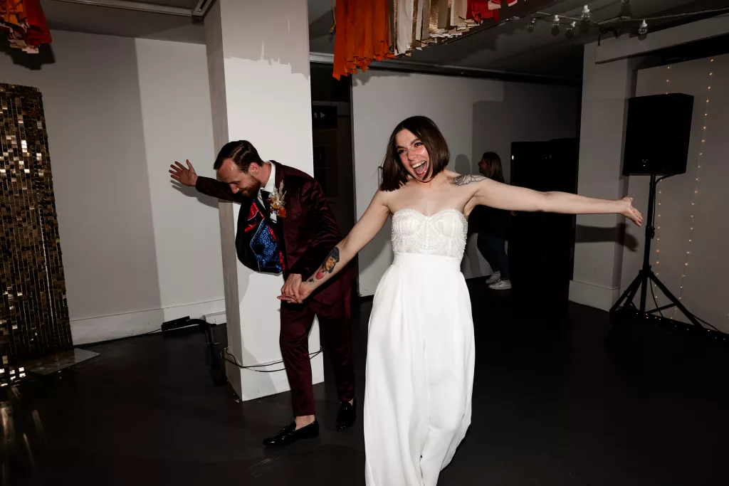 Bride & Groom walking into their evening reception. The bride has changed out of her wedding dress and into a fun jumpsuit ready for the party
