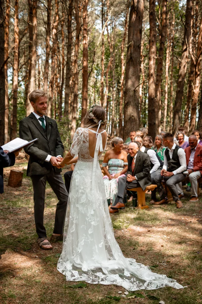 The Bride & groom smiling during her wedding ceremony at Harvest Moon wedding venue in Scotland. The bride is wearing a rembo styles wedding dress and flower crown