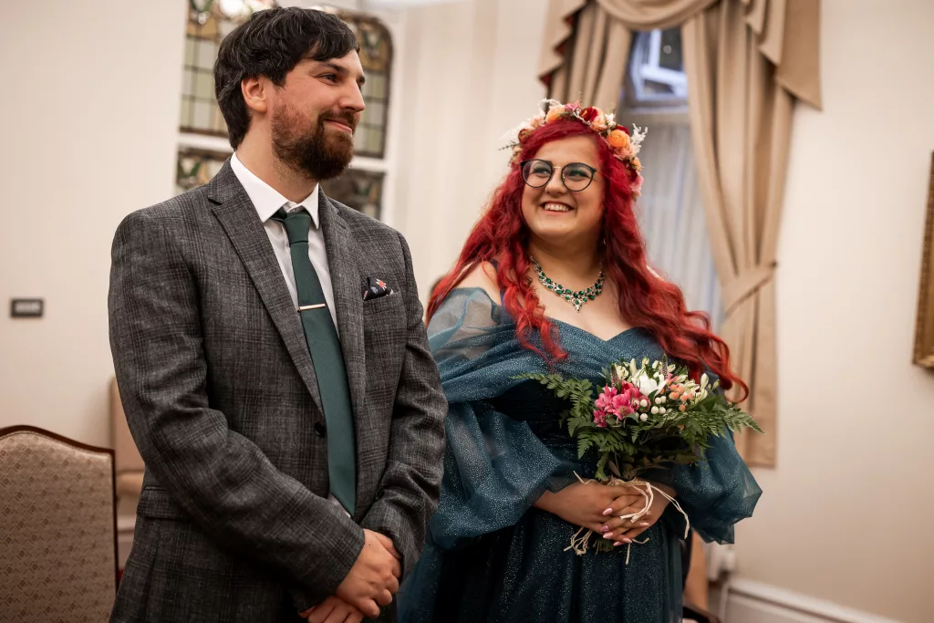 Bride and groom stood together during their wedding ceremony at Dukenfield town hall. The bride wearing an alternative vibrant blue wedding dress