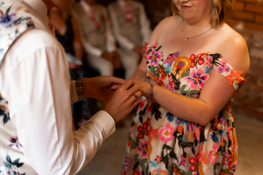Close up during the wedding ceremony rings. The bride is wearing a bright and colourful flower wedding dress