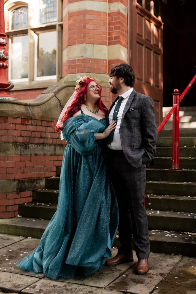 Bride and groom stood together outside Dukenfield town hall after their wedding ceremony. The bride wearing an alternative vibrant blue wedding dress