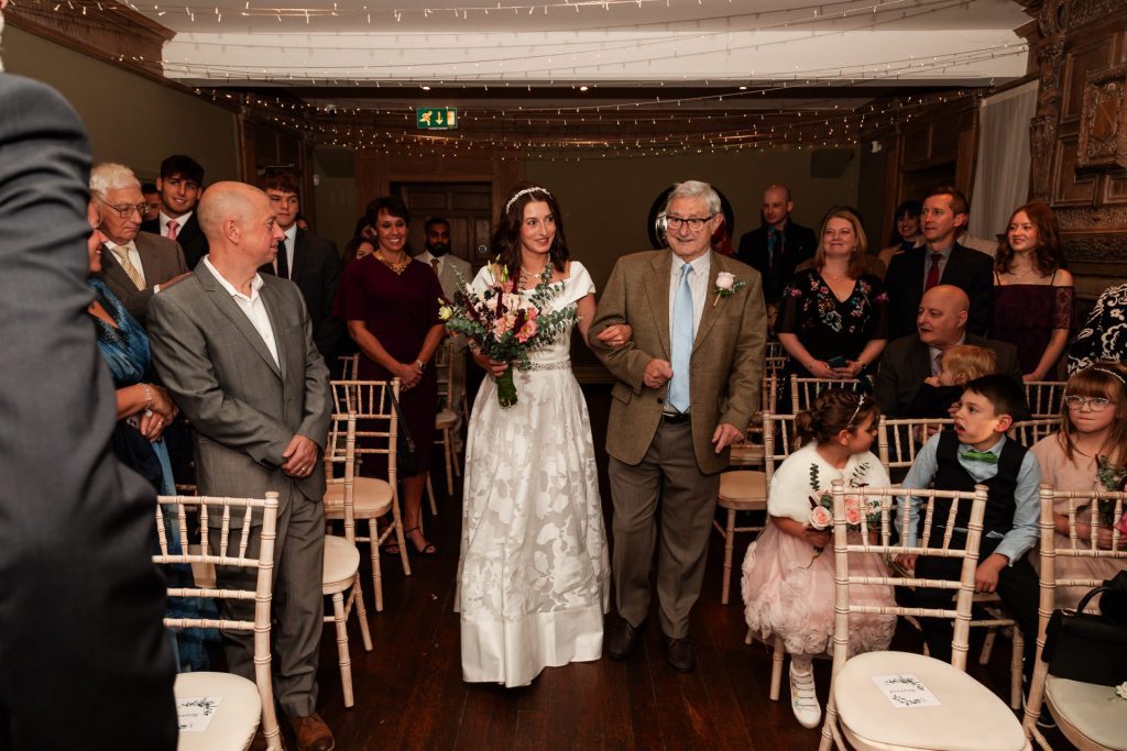 The bride and the father of the bride walking together up the aisle at Whirlowbrook Hall Wedding venue- Isabelle B Photography