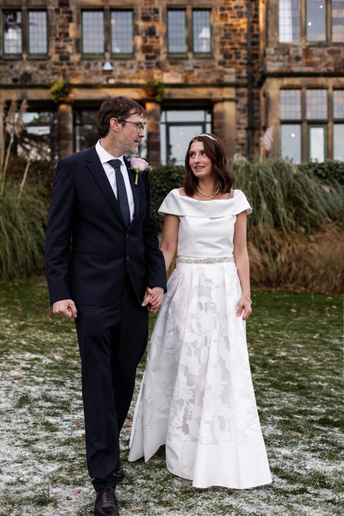 The bride and groom walking together outside their wedding venue - Whirlowbrook Hall - Isabelle B Photography
