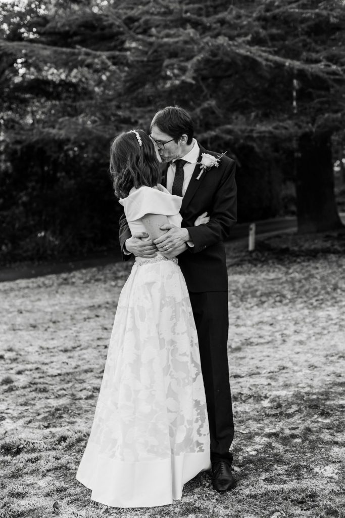 The bride and groom embraced in a kiss outside their wedding venue - Whirlowbrook Hall - Black & White - Isabelle B Photography