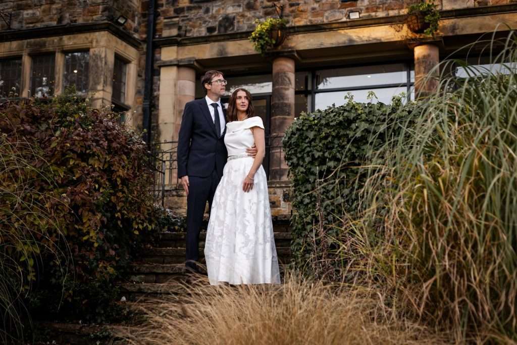 The bride and groom stood together outside their wedding venue - Whirlowbrook Hall - Isabelle B Photography