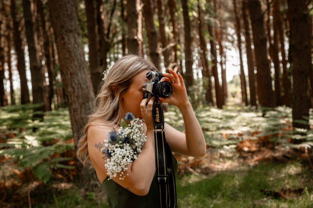 Bridesmaid taking a photo on an analogue film camera after a wedding ceremony at Harvest Moon - Wedding Photography - Isabelle B Photography
